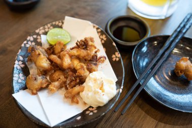 Mayonez ve limonlu kızarmış mürekkep balığı dokunaçları, popüler içkilerle birlikte yenen Japon yemekleri olan sosları batırıyor..