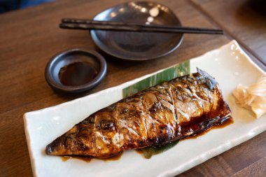 Ahşap bir tabakta beyaz bir tabakta yanında sos ve çubuk ile ızgara saba balığı popüler bir Japon yemeğidir..