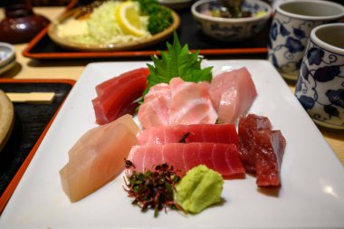 Japon restoranının masasındaki beyaz tabağa wasabi ve sebzeli balık sashimi.