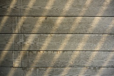 Eski ahşap duvarda su lekeleri var ve yukarıdan süzülen ışıkla kirli görünüyor..