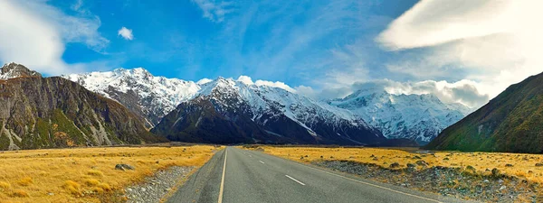 Dümdüz dağlara giden yol, kışın karla kaplı kayalık tepeler ve ulusal park alanında gün boyunca güzel bulutlar, Cook Dağı, Yeni Zelanda.