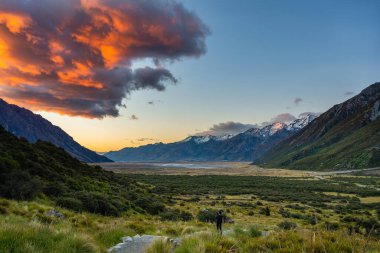 Yüksek dağlarda fotoğraf çeken turistler güzel manzaranın, sabah gökyüzünün ve Yeni Zelanda 'daki Cook Dağı Ulusal Parkı' nda güzel dramatik bulutların tadını çıkarıyorlar..