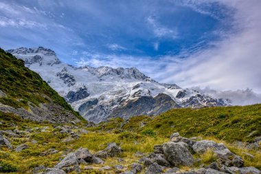 Mount Cook Ulusal Parkı 'ndaki Kea Point Pisti, Yeni Zelanda' da yaz aylarında yüksek kayalık dağlar ve yeşil çimenler