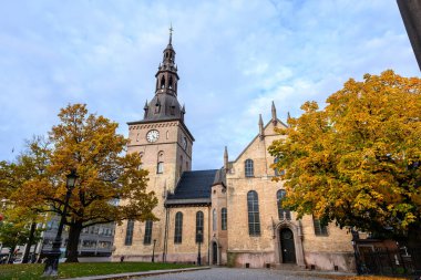 Sonbaharda Oslo Katedrali 'nin avlusunda yaprakların bahçesindeki ağaçlar sararır ve turuncuya döner. Güzelim, akşamları gökyüzü bulutlarla mavidir..
