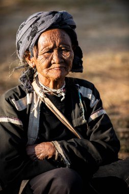 Chiang Mai / Tayland - 16 Ocak 2016: Buruşuk görünüşlü yaşlı kadın, kabile gibi giyinmiş, kolları kavuşturulmuş ve gülümsüyor. Kuzey Tayland 'da bir köy.