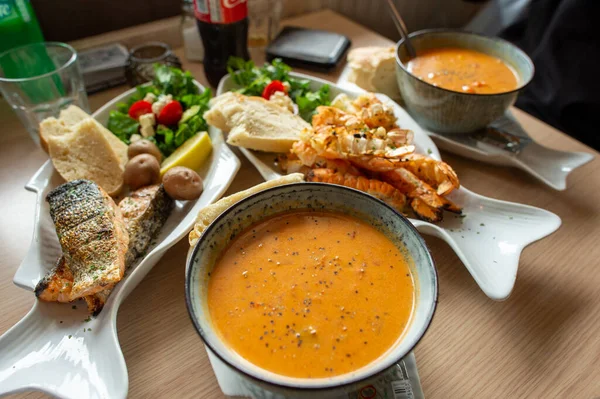 Langoustine çorbası ve Langoustine beyaz balık şeklinde tabakta tuzlu ızgara. Yemek masasına güzel ekmekler ve sebzeler koyun. İzlanda 'nın güneyindeki bir restoranda.