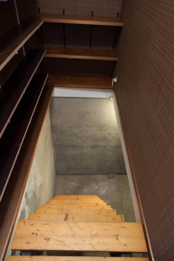 Terk edilmiş eski sanayi binasının bodrumunda az ışık ve ahşap merdivenler var.