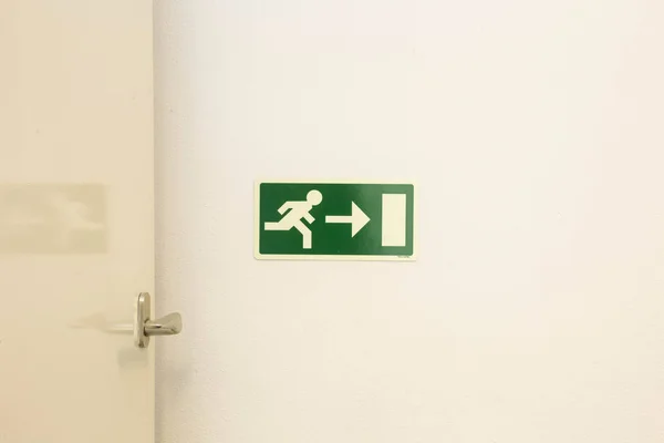 The emergency exit sign shows the direction of escape in case of danger. The emergency exit board hangs on the ceiling of the building.