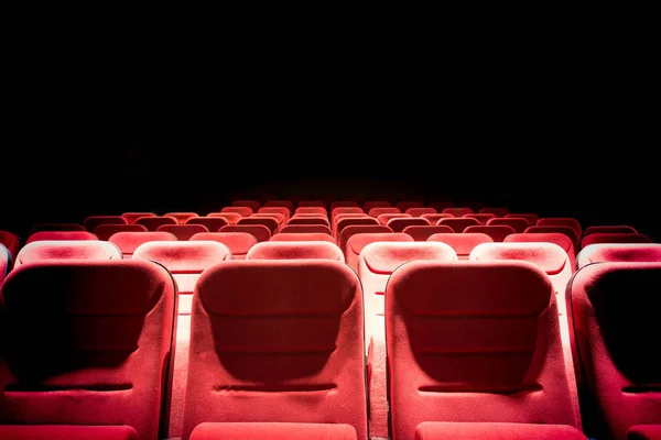 Dark movie theater with projection light and empty red seats — Stock Photo, Image