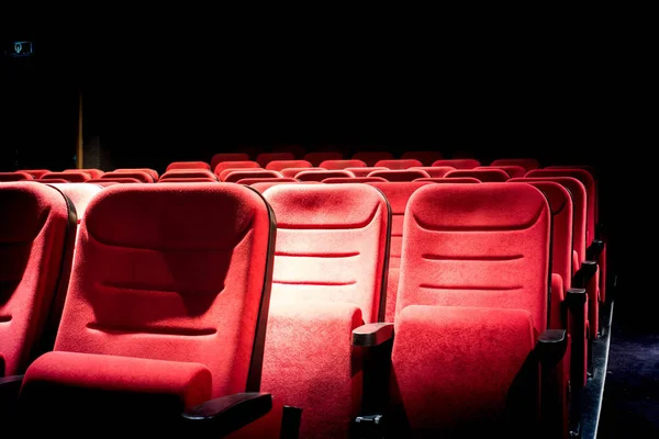 Cine oscuro con luz de proyección y asientos rojos vacíos — Foto de Stock