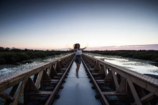 Модная брюнетка женщина прыгает на городской мост с закатом счастливой здоровой жизни — стоковое фото