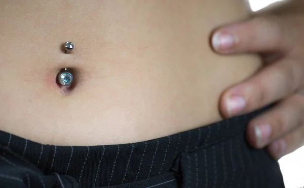 Dettaglio della pancia di una giovane donna, con un piercing all'ombelico — Foto Stock