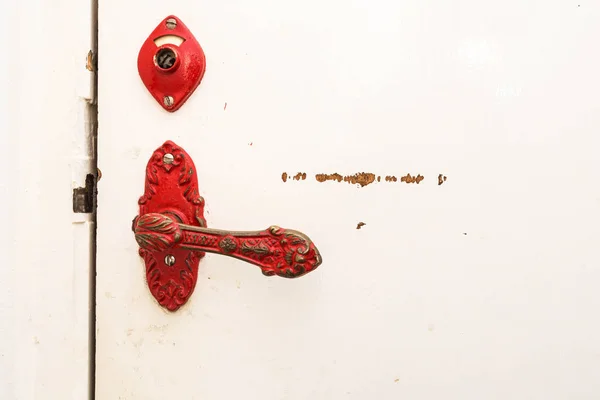 Ancient red door handle on a white broken old door close-up vintage design — Stock Photo, Image