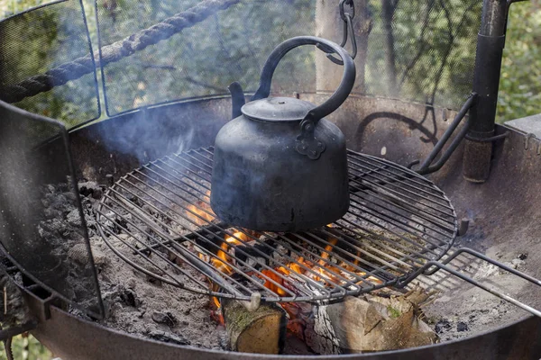 Matlagning vattenkokare på eld lågan brinnande utomhus i skogen resor livsstilskoncept semester — Stockfoto