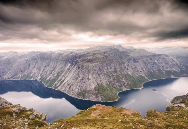 Pemandangan gunung yang dramatis dan kasar pada hari yang mendung dengan danau yang tenang — Stok Foto