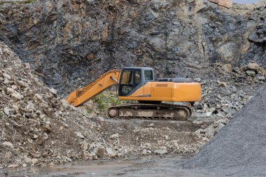 İnşaat alanında taş ocağında büyük bir sarı renkli kazıcı var.