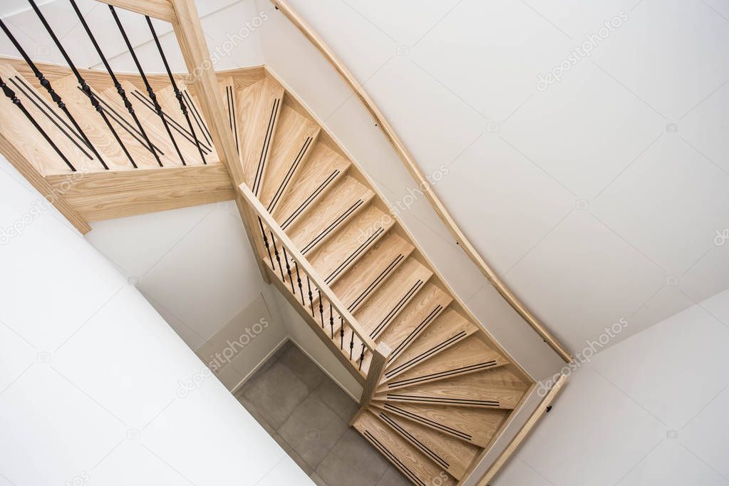 luxurious modern wooden staircase with curved landing wall in a house