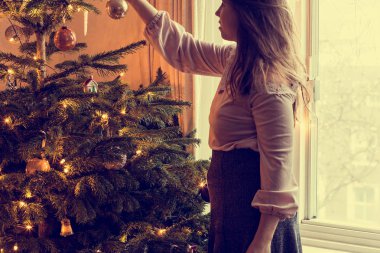 Genç kadın bir Noel ağacı geleneği tatil güzellik süsle