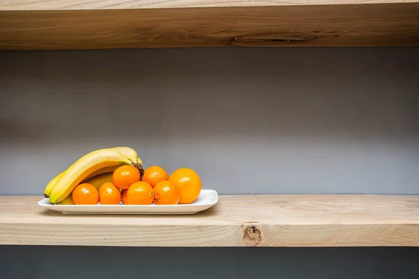 Rak dengan berbagai hal dan buah-buahan di atas meja, pisang segar dan oranye — Stok Foto