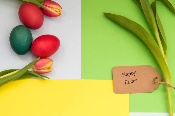 Пасхальные яйца окрашены и тюльпаны с желтым зеленым фоном и текст счастливой Пасхи — стоковое фото