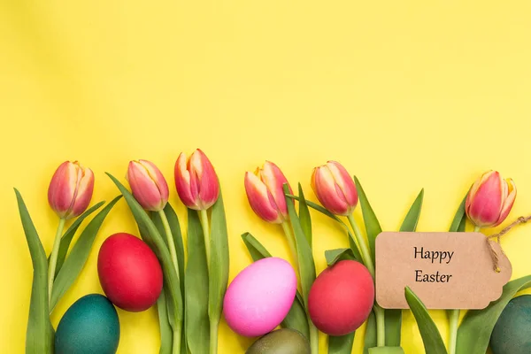 Пасхальные яйца окрашены и тюльпаны с желтым фоном и текст счастливой Пасхи — стоковое фото