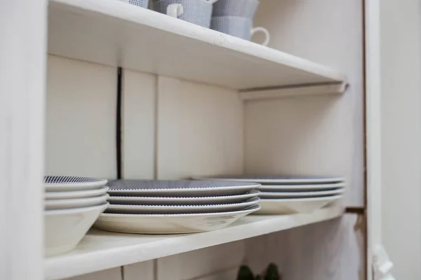 Посуда на деревянной полке, тарелки и чашки в шкафу — стоковое фото