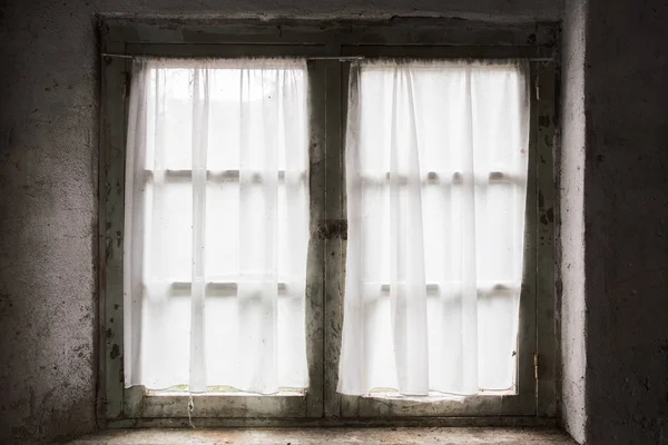 Vieille fenêtre sombre avec briques et rideau, la lumière passe à travers — Photo