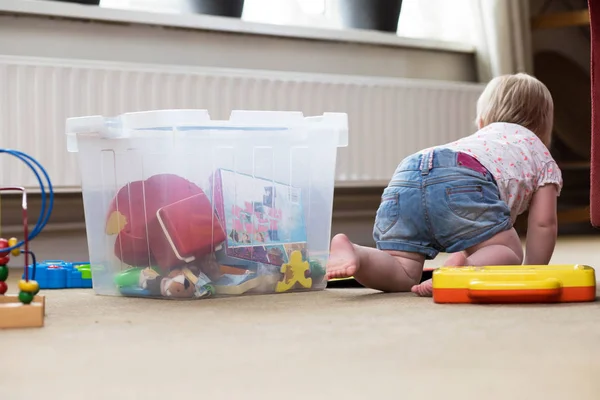 Bebê brincando sozinho com brinquedos em um tapete no chão em casa — Fotografia de Stock