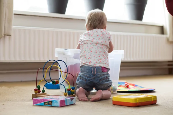 Dítě hraje sám s hračkami na koberci na podlaze doma — Stock fotografie