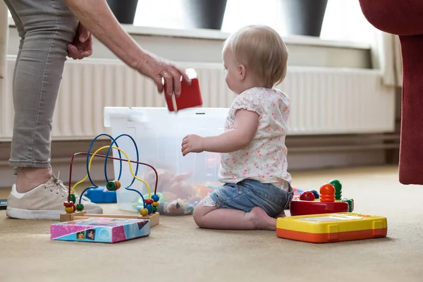 Nagymama és baba a játékokkal a padlón a nappaliban — Stock Fotó