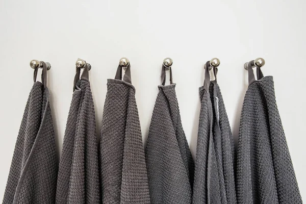 Серые полотенца, висящие в ряд, приготовленные на вешалке. белая стена — стоковое фото