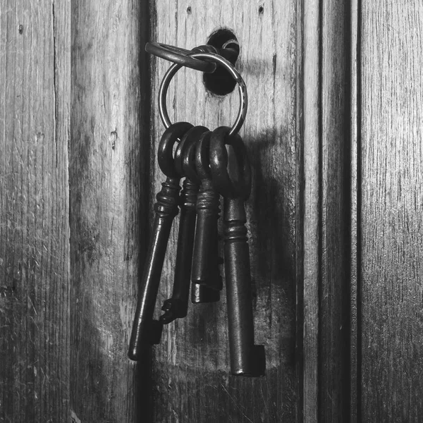 Old rusty keys inside a keyhole of an old antique closet. vintage design black and white — Stock Photo, Image