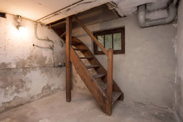 Sótano vacío en antiguo edificio industrial abandonado con poca luz y unas escaleras de madera — Foto de Stock