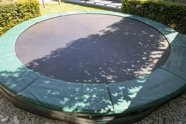 Grünes Trampolin auf dem Rasen im Garten in Großaufnahme leer — Stockfoto