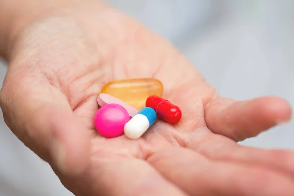 Många flerfärgade piller i ett seniorer händer. Smärtsamma ålderdom. Ta hand om hälsan hos äldre — Stockfoto