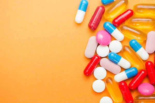 Sortierte pharmazeutische Medikamententabletten, Tabletten und Kapseln sowie Flasche auf orangefarbenem Hintergrund. Kopierraum für Text — Stockfoto