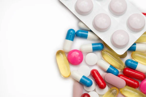 Valikoima lääkkeitä pillereitä, tabletit ja kapselit ja pullo valkoisella pohjalla. Kopioi tilaa tekstille — kuvapankkivalokuva