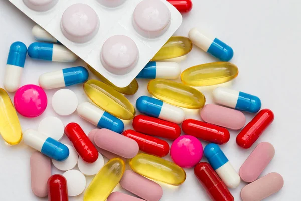 Valikoima lääkkeitä pillereitä, tabletit ja kapselit ja pullo valkoisella pohjalla. Kopioi tilaa tekstille — kuvapankkivalokuva