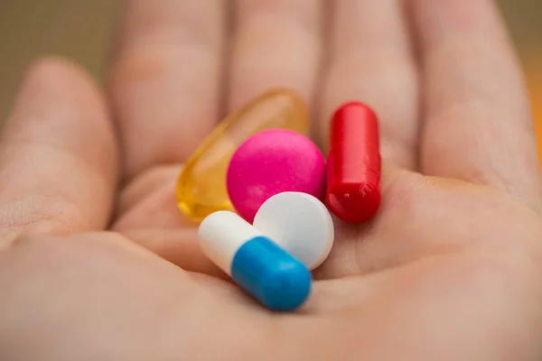Pillen in verschiedenen Farben in jungen Händen, Einnahme von Medikamenten. — Stockfoto