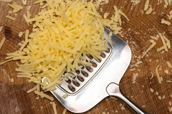 Rallador de queso metálico y queso en tabla de cortar de madera , —  Fotos de Stock