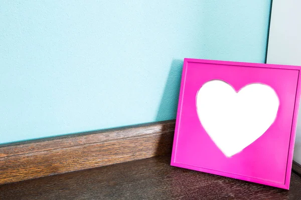 Różowy serce zdjęcie ramki na drewnianym stole z niebieskim tle ściany, miejsce na tekst — Zdjęcie stockowe