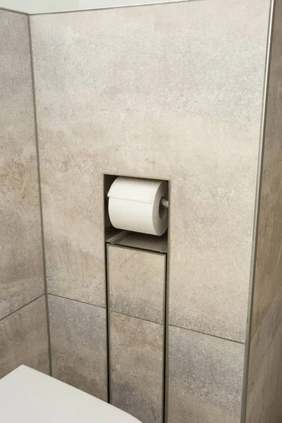 Een witte Roll van zacht toiletpapier dat netjes op een moderne chroom houder in de muur hangt — Stockfoto