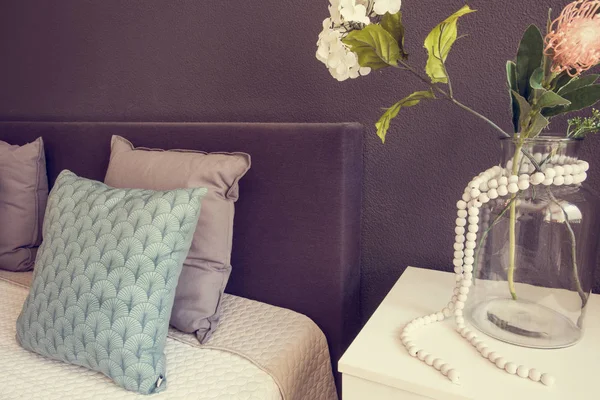 Cama hecha con almohadas limpias y sábanas en la sala de belleza. con jarrón de vidrio y flores decorativas —  Fotos de Stock
