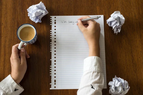 Mi dispiace scritto su carta con caffè su tavolo di legno mani di una persona — Foto Stock