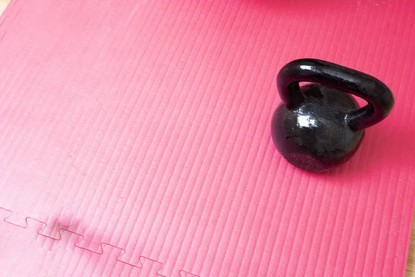 Kettlebell e tappetino yoga rosa sul pavimento, spazio concettuale sportivo per il testo — Foto Stock