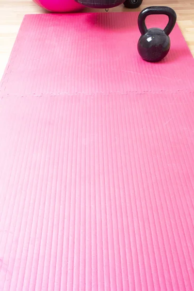 Kettlebell e tappetino yoga rosa sul pavimento, spazio concettuale sportivo per il testo — Foto Stock