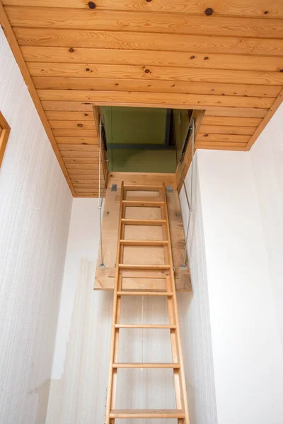 Wooden folding ladder to the attic, old empty house