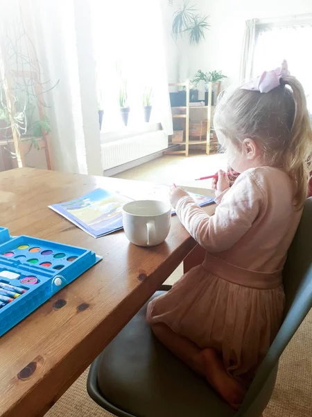 Retrato de pintura menina na sala de estar em seu vestido rosa na mesa de madeira — Fotografia de Stock