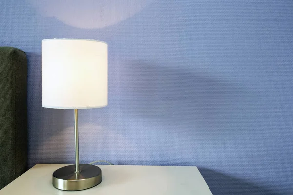 Lampe veilleuse sur une table de nuit avec mur bleu, espace pour le texte — Photo