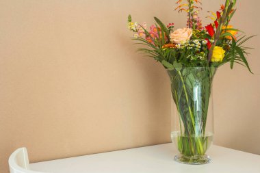 Açık kahverengi duvar, metin için alan ile beyaz masada güzel çiçek buketi